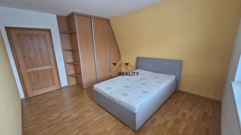 A bedroom with a wood-decor floor in a 3-room apartment, equipped with a bed and a built-in wardrobe.