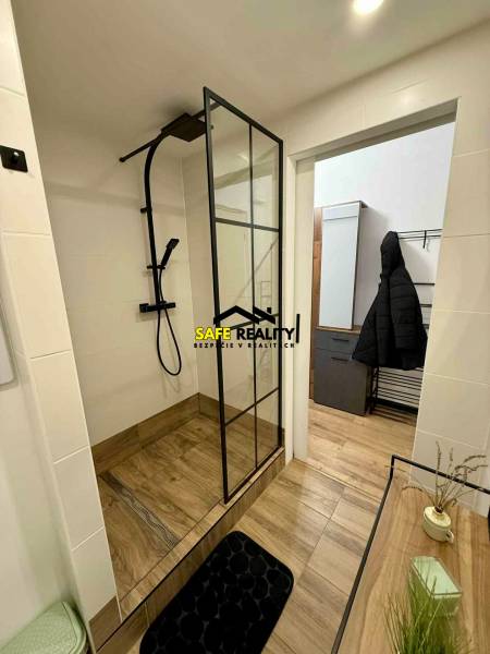 A bathroom with a shower and a wooden decor floor in a studio apartment.