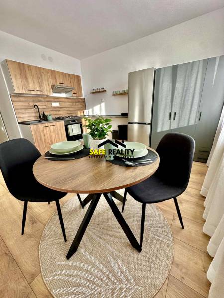 A kitchenette in a studio apartment with a wooden decor and a round table.