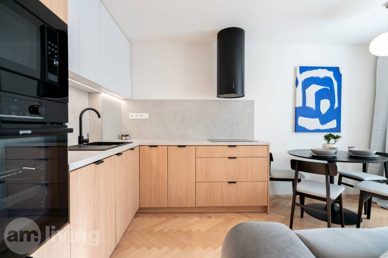 A kitchen with a wood-patterned floor, wooden cabinets, and a dining table in a three-room apartment.