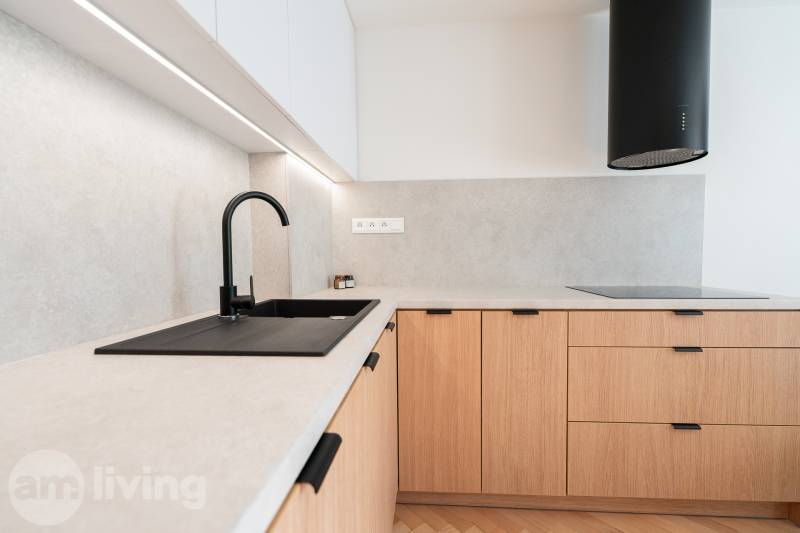 A kitchen unit in a 3-room apartment with a wooden decor floor and a black sink.