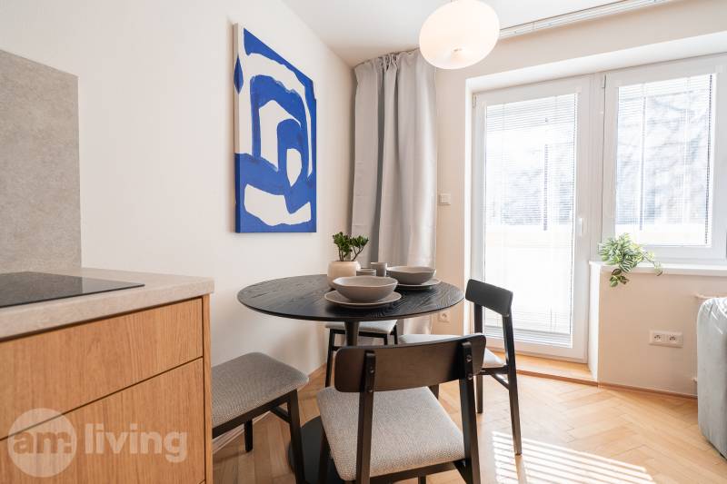 Dining area in a 3-room apartment with a round table and a painting on the wall.
