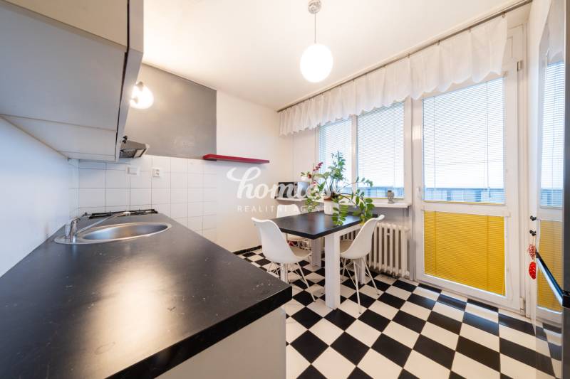 A kitchen in a 3-room apartment with black and white tiles, a dining table, and large windows.