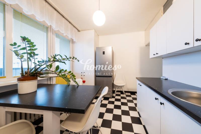 The kitchen with a black and white floor in a 3-room apartment contains a plant and a dining table.