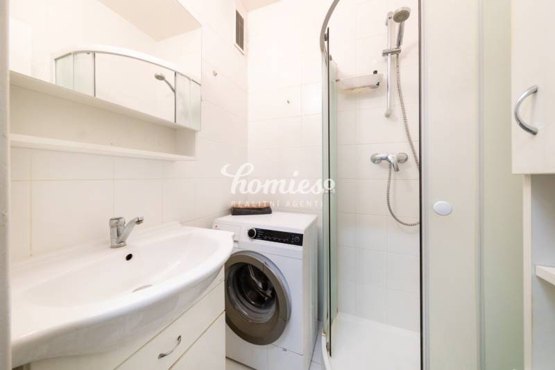 A bathroom with a shower and a washing machine in a 3-room apartment.