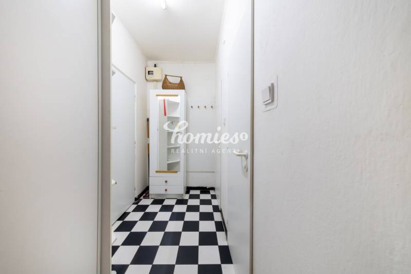 A narrow hallway with a black-and-white floor in a 3-room apartment with storage space.