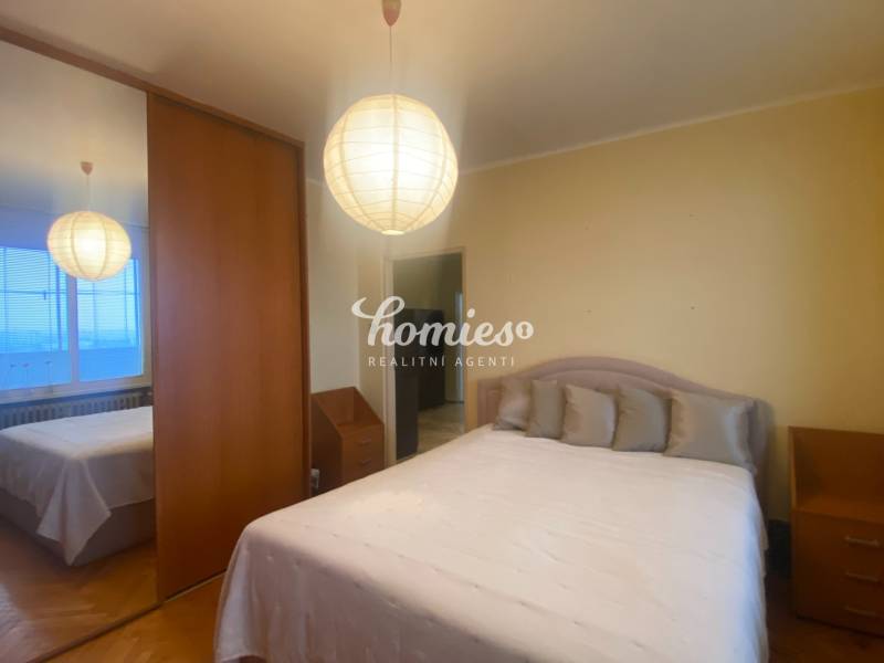 Bedroom in a 3-room apartment with a wardrobe, bed, and floor with a wooden decor.