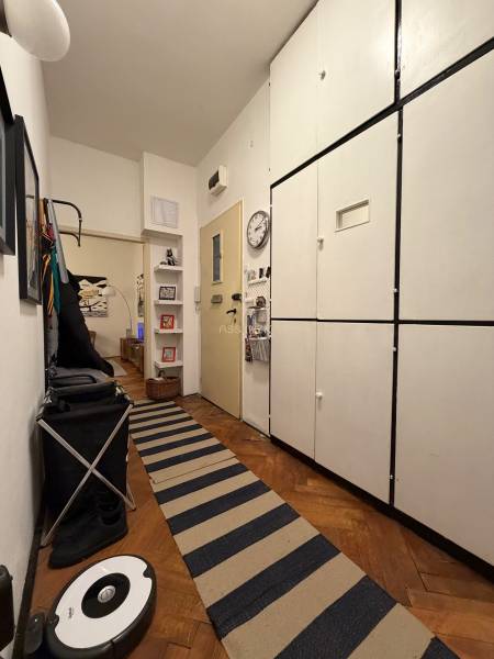 A hallway in a 2-room apartment with a wooden decor floor and storage cabinets.