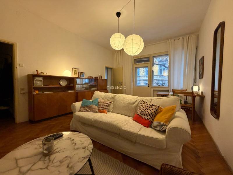 Living room in a two-room apartment with a wooden decor floor and a comfortable sofa.