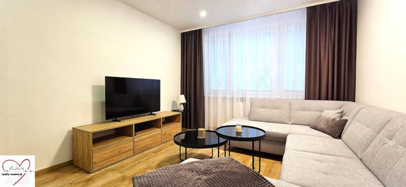 Living room in a three-room apartment with a sofa, television, and a coffee table on a floor with a wooden decor.