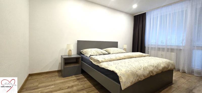 Bedroom with a bed, nightstand, and wooden decor flooring in a 3-room apartment.