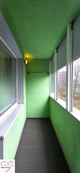 Glazed loggia with tiles in a 3-room apartment. The walls are painted green.