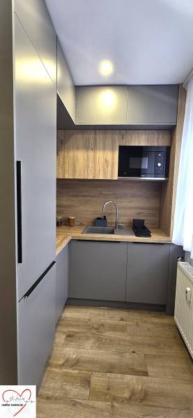 A kitchen in a 3-room apartment with a wooden decor floor, built-in microwave.