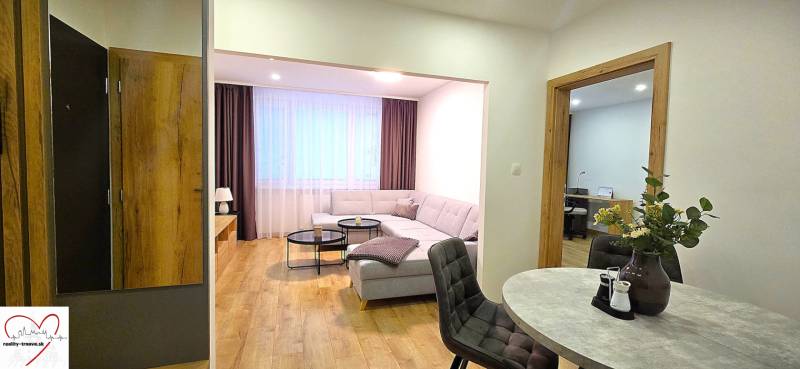 Living room of a three-room apartment with a sofa, table, and floor with a wooden decor.