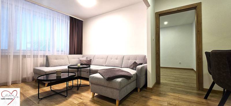 Living room with a comfortable sofa and a wooden-patterned floor in a 3-room apartment.