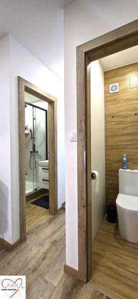 A hallway with a wooden decor floor, two rooms, a bathroom, and a toilet in a 3-room apartment.