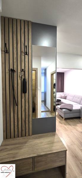 Hallway with a mirror, coat rack, and a view into the living room. Floor with a wooden decor.