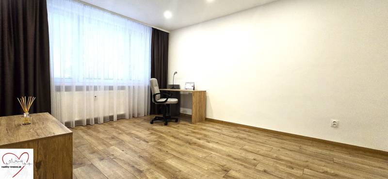 A workspace with a desk in a 3-room apartment with a wooden decor floor.