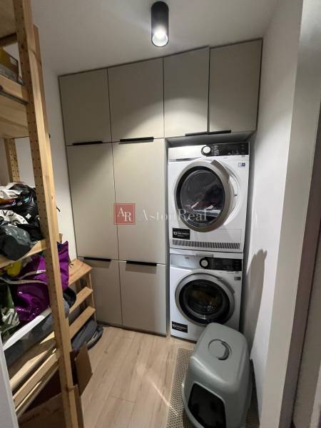 Laundry room with lockers, washing machine, and dryer in a 4-room apartment. Floor with wood decor.