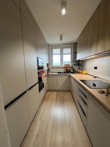 A kitchen in a 4-room apartment with a wooden decor floor, light cabinets, window.