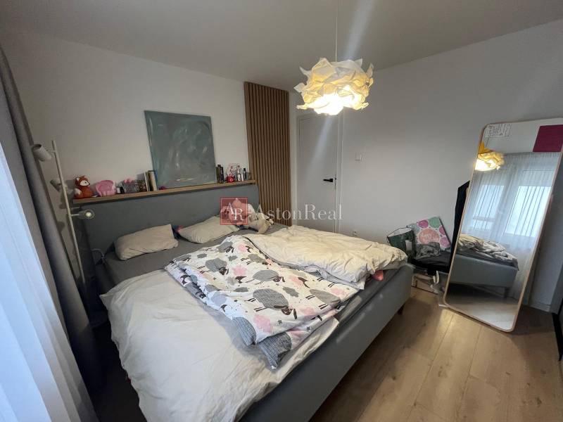 Bedroom in a 4-room apartment with a comfortable bed and a floor with a wooden decor.