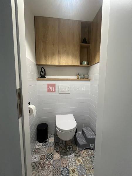 A bathroom in a 4-room apartment with colorful tiles and wooden cabinets on the walls.