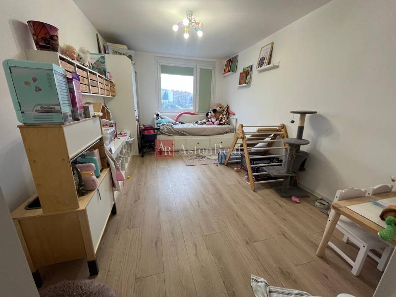 Children's room in a 4-room apartment with a wooden decor floor, toys, and a bed.