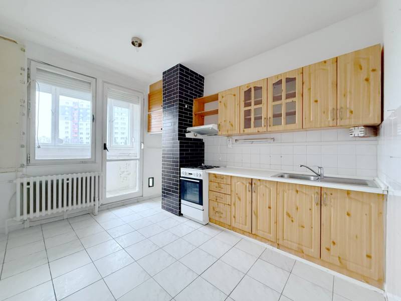 A kitchen with light tiles, wooden cabinets, and white appliances in a 4-room apartment.