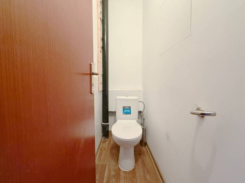 A toilet with a wooden decor floor in a 4-room apartment.