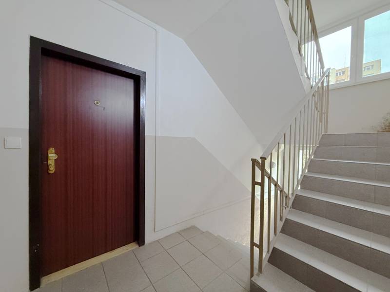 Staircase and entrance door to a 4-room apartment with a window on the staircase.