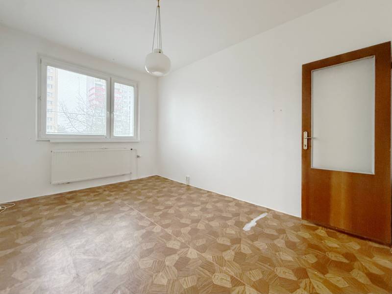 A room with a bright window and a floor with a wooden decor, 4-room apartment.