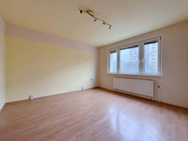 An unfurnished room with wood-patterned flooring and a large window in a 4-room apartment.