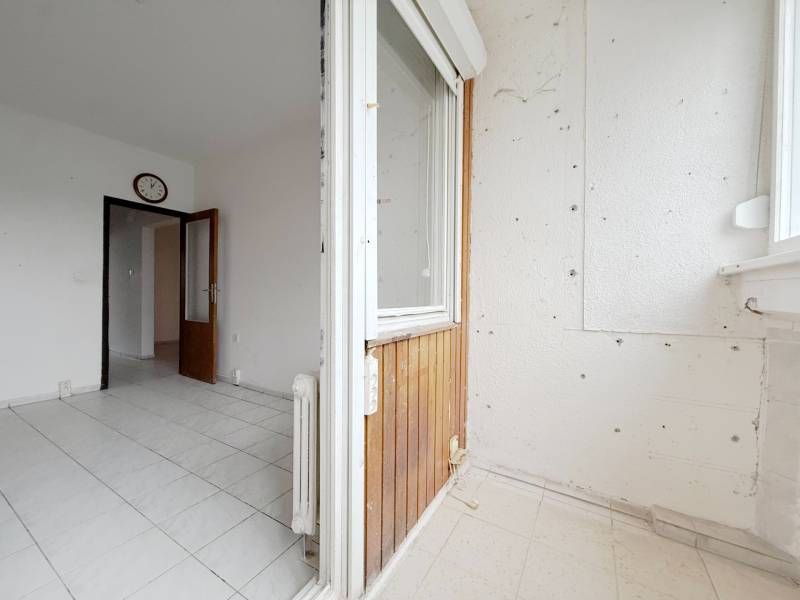 A balcony with tiles in a 4-room apartment, view into the hallway with doors.