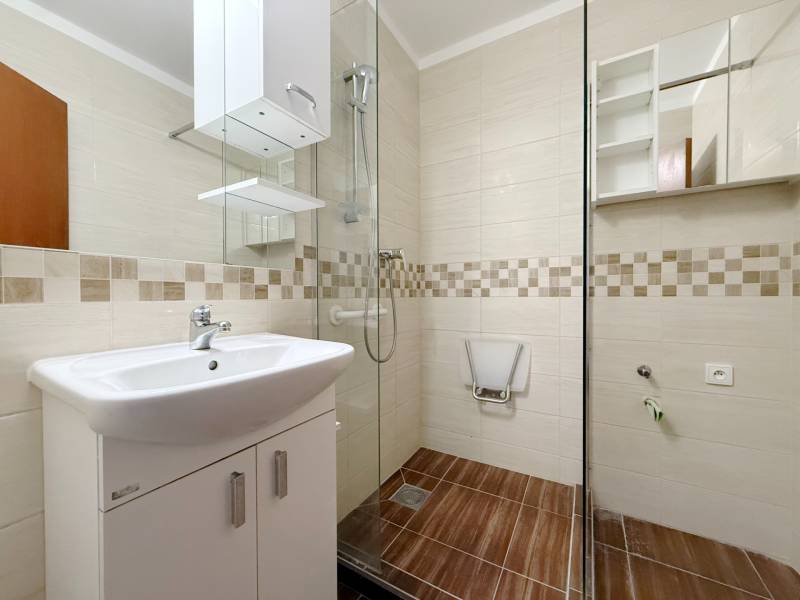Bathroom with a shower and a sink in a 4-room apartment, floor with wood decor.