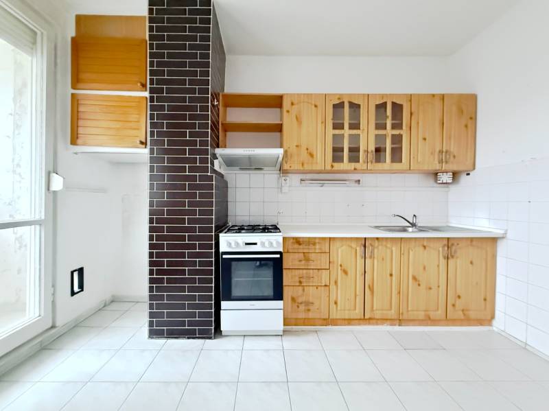 A kitchen with wooden cabinets, a stove, and a white floor in a 4-room apartment.