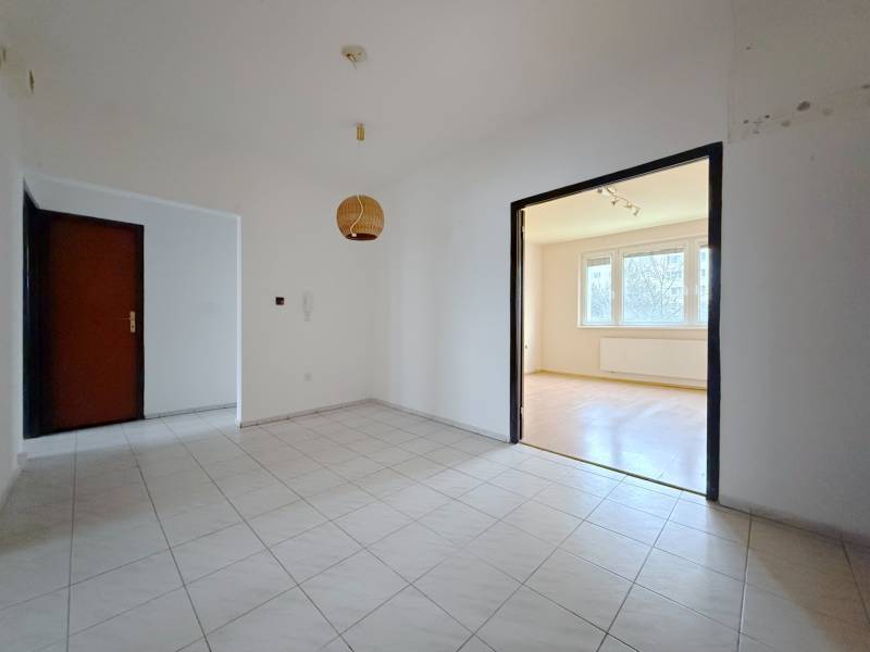 A tiled hallway leads to a bright living room with access to a floor with a wooden decor.