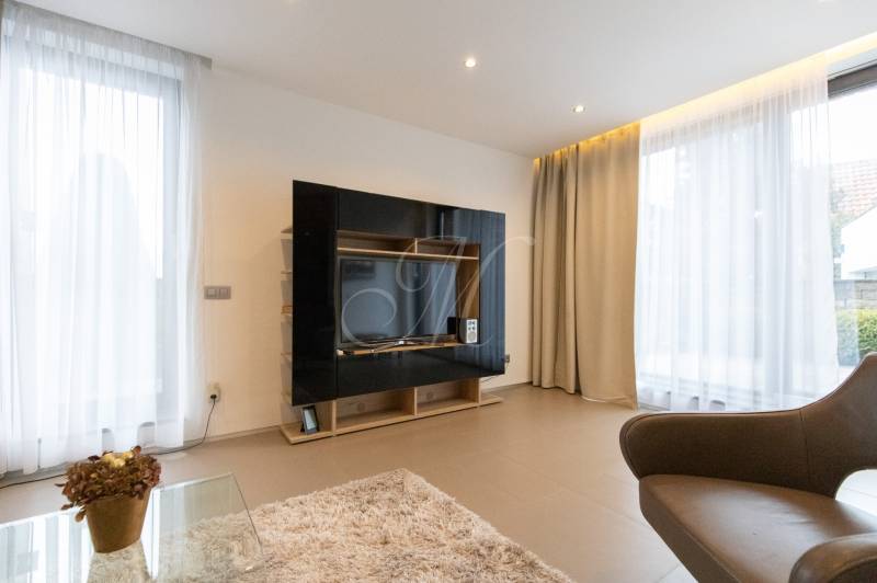 Living room in a two-room apartment with light curtains and a TV wall.