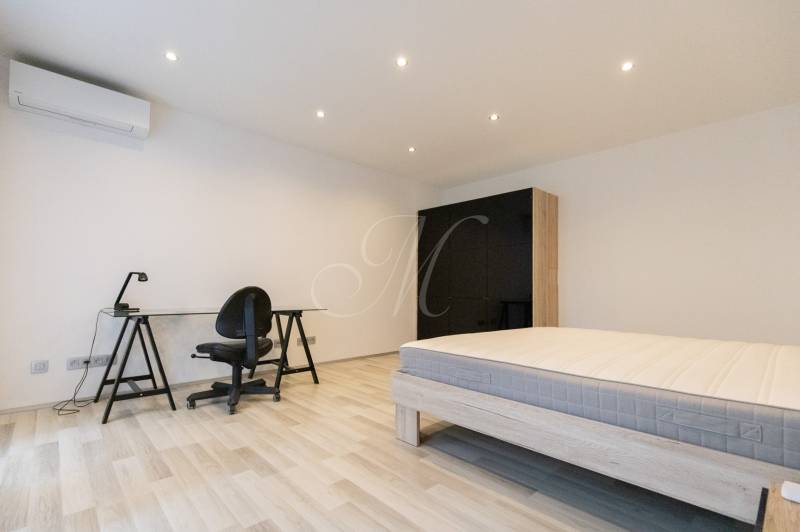 A bedroom in a two-room apartment with simple furniture and a wooden decor floor.