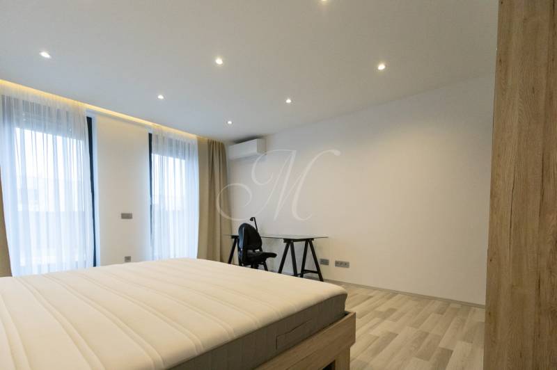 A bedroom in a two-room apartment with a bed, a table, and a floor with a wooden decor.