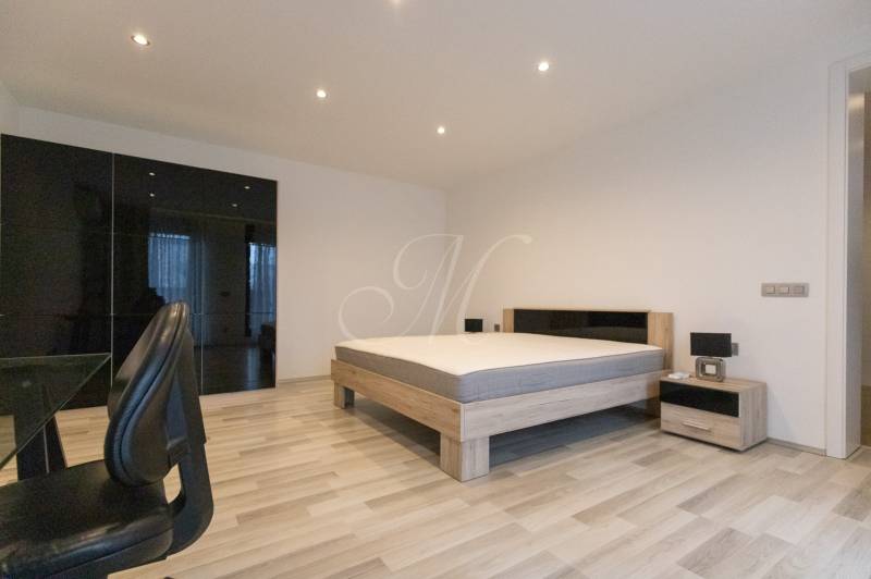 2-room apartment with wood-patterned flooring, a bed, a wardrobe, and an office chair.