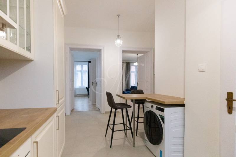 Hallway in a 3-room apartment with a washing machine, chairs, and a kitchen unit.