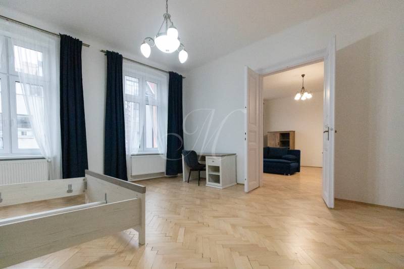 Interior of a 3-room apartment with wood-decor flooring, furniture, and a chandelier.