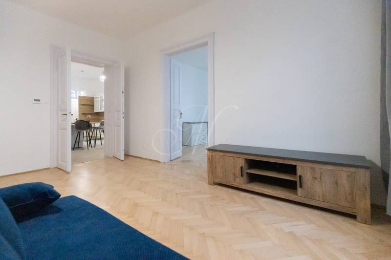 Living room of a three-room apartment with a blue sofa and a wooden decor floor.