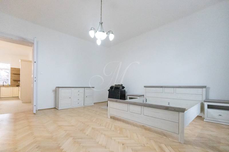 A bedroom with a bed, furniture, and flooring with a wooden decor in a 3-room apartment.