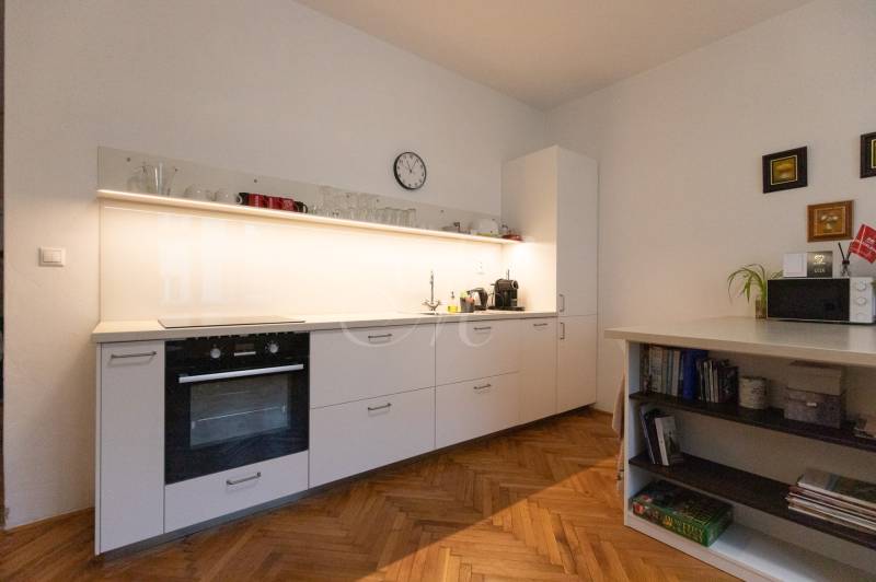 Kitchen in a 2-room apartment with white cabinets and a wooden decor floor.