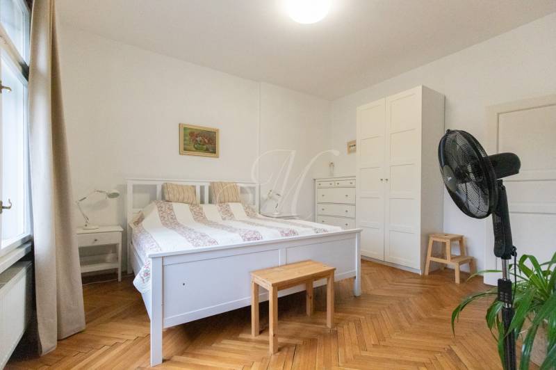 A bedroom in a 2-room apartment with white furniture and a wooden decor floor.