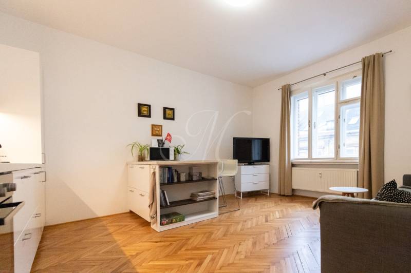 Living room in a two-room apartment with light furniture and a wooden decor floor.