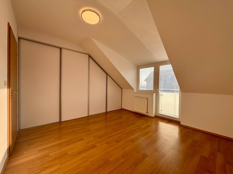 Attic room in a 2-room apartment with a wooden decor floor and a built-in wardrobe.