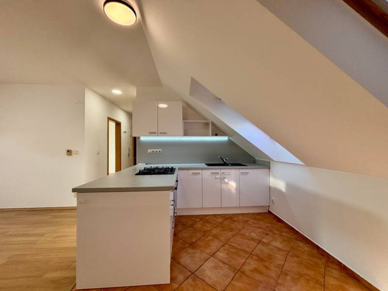 A kitchen in a 2-room apartment with a kitchen unit and a ceramic tile floor.
