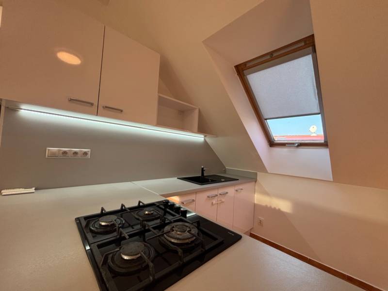 Kitchen in a 2-room apartment, built-in stove, sink, skylight, white cabinets.